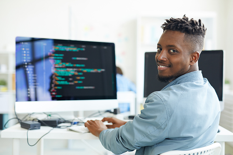 Smiling male at a computer coding software